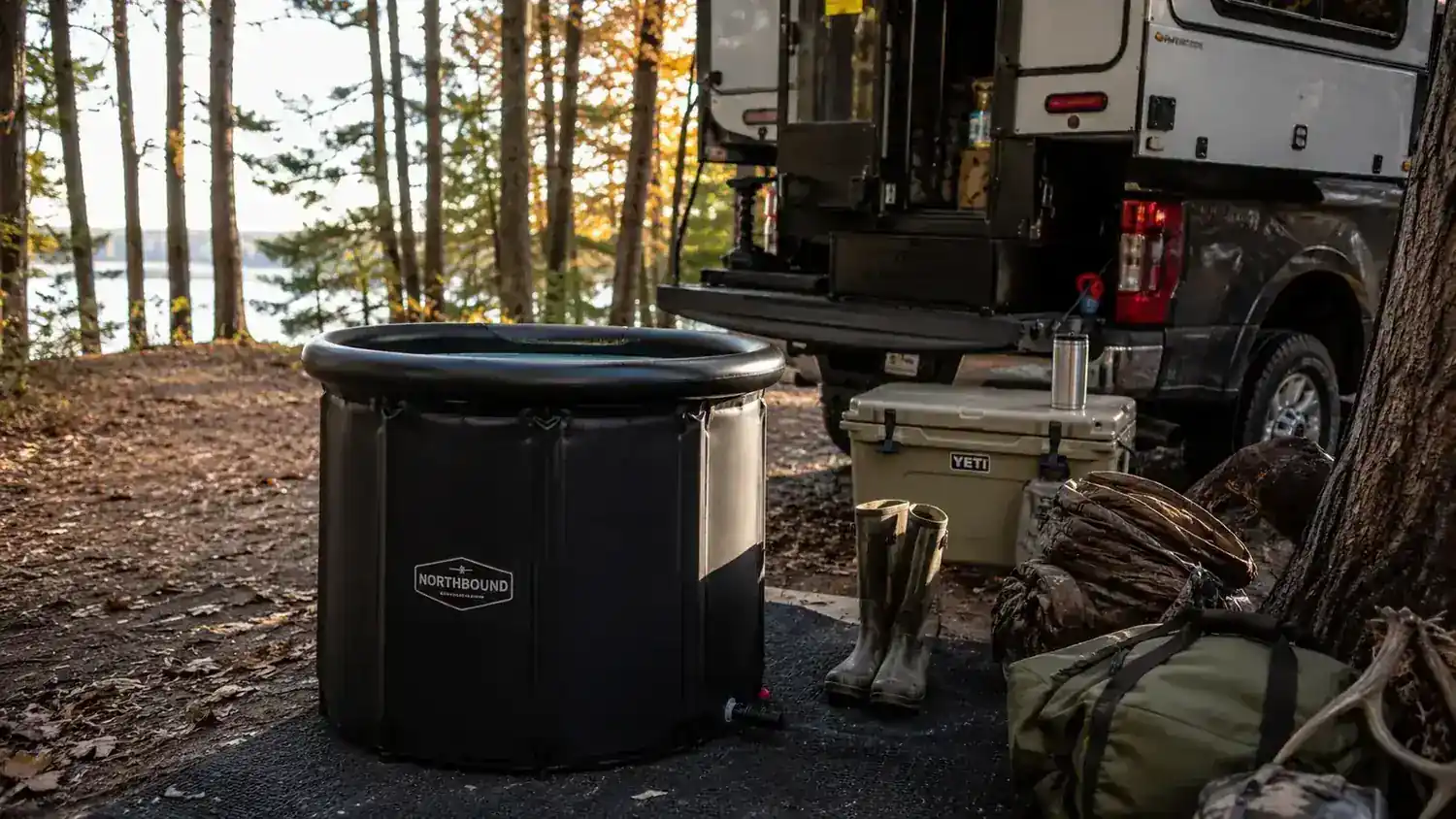 Cold plunge tub set up outside a camper at a hunting camp with wooded hills in the background