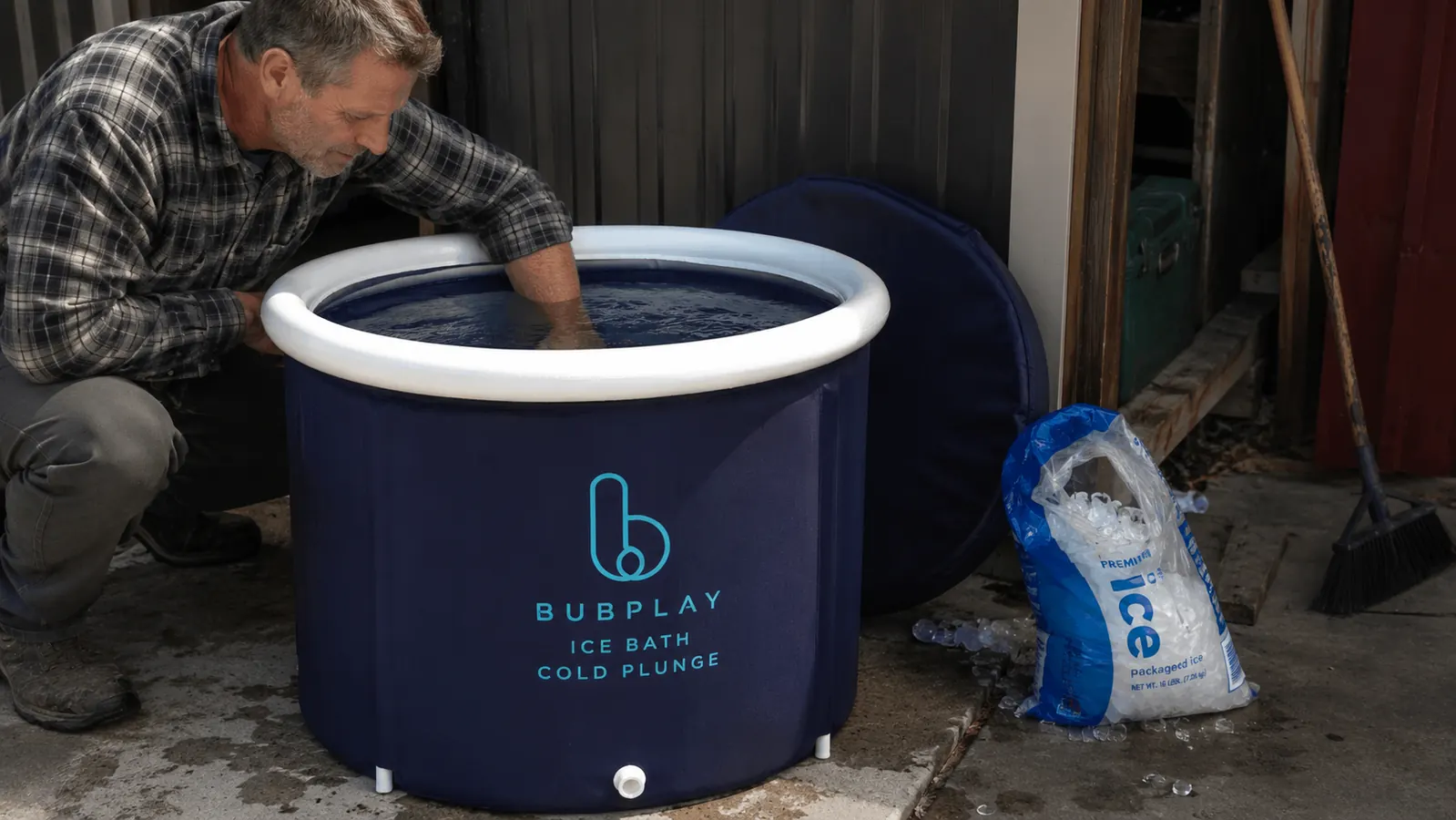 Close-up of a hand testing water temperature in the cold plunge tub with a bag of ice nearby